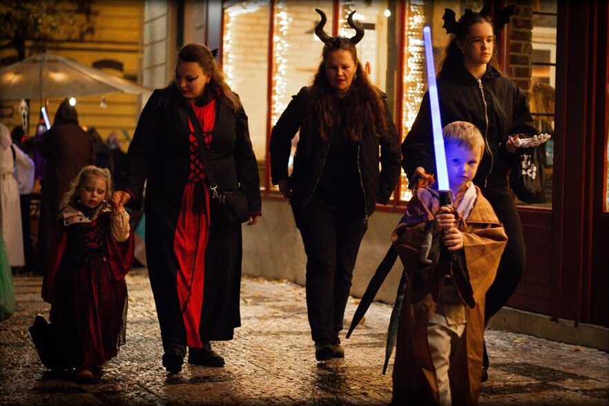 Trick-or-treaters in costumes on an evening street in Vinohrady