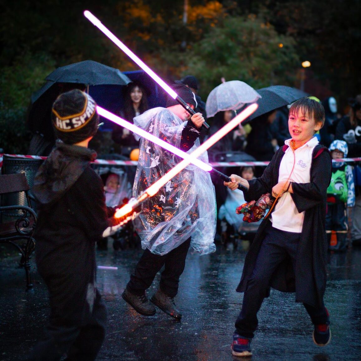 Children duelling with glowing lightsabers in the rain