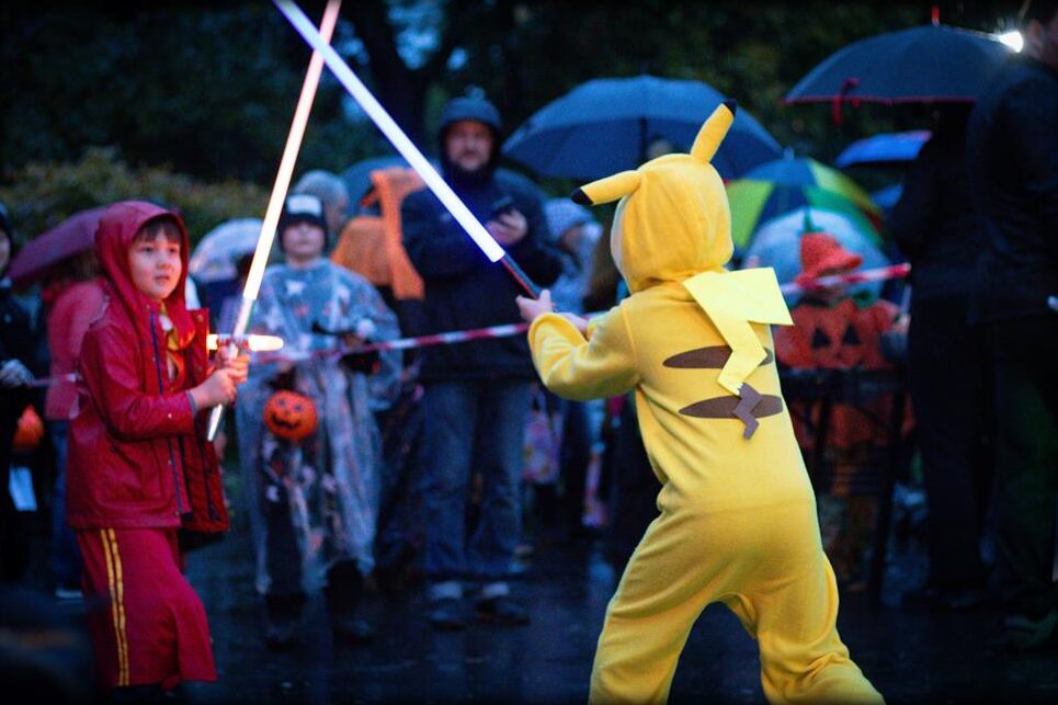 Lightsaber arena in the park, kids in costumes under umbrellas