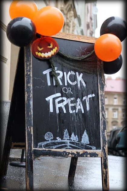 Chalkboard sign saying Trick or Treat with orange balloons