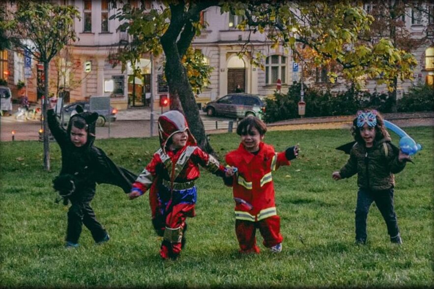 Children in costumes running across the grass in the park